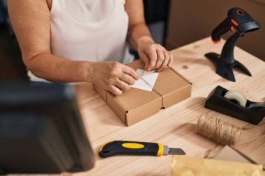 Middle age woman ecommerce business worker preparing package at office