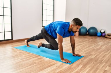 Yakışıklı İspanyol adam egzersiz yapıyor ve yoga minderinde geriniyor. Spor salonunda esneklik ve antrenman yapıyor.