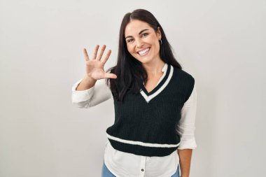İzole edilmiş arka planda duran genç İspanyol kadın beş numarayı gösterip işaret ederken kendinden emin ve mutlu bir şekilde gülümsüyor.. 
