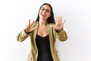 Genç esmer kadın izole edilmiş arka planda duruyor. Sekiz numaralı parmaklarıyla işaret ediyor ve gülümsüyor. Kendinden emin ve mutlu.. 