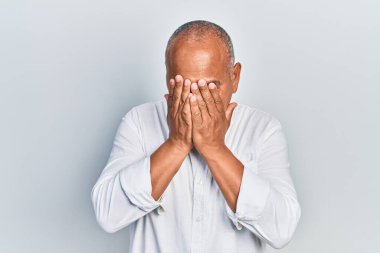 Orta yaşlı, sıradan kıyafetler giyen, suratını ellerle örten ve ağlayan bir Latin. depresyon kavramı. 