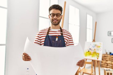 Genç Arap sanatçı gülümsüyor. Resim stüdyosunda mutlu bir beraberlik var..
