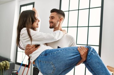 Genç İspanyol bir adam yeni evinde kadını kollarında tutuyor..