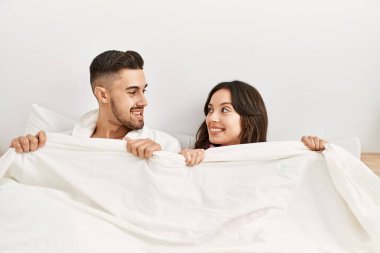 Genç İspanyol çift yatakta yatıp çarşafla örtüyor..