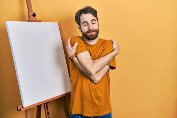 Caucasian Man Beard Standing Painter Easel Stand Hugging Oneself Happy — стоковое фото