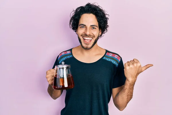 Handsome Hispanic Man Holding Traditional Tea Pot Pointing Thumb Side — 스톡 사진