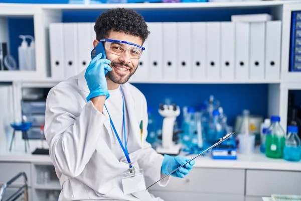 Young Arab Man Wearing Scientist Uniform Talking Smartphone Laboratory — Stok fotoğraf