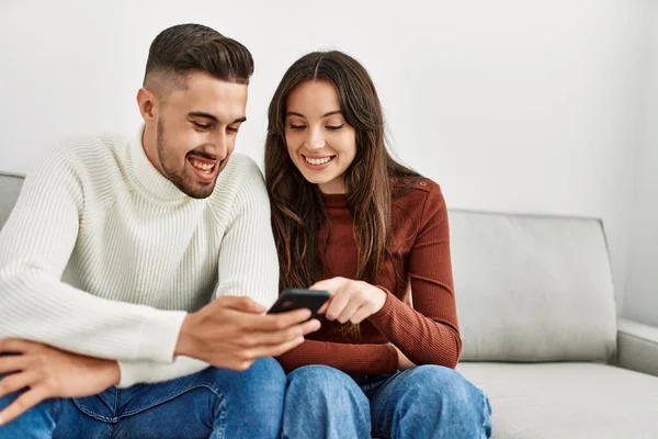 Jong Hispanic Paar Met Behulp Van Smartphone Zitten Bank Thuis — Stockfoto