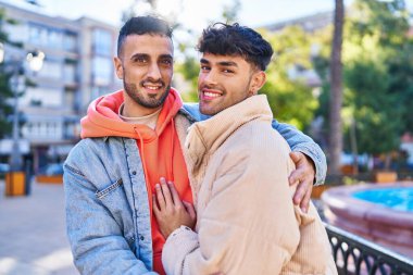 İki erkek parkta birbirlerine sarılıyorlar.