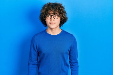 Yakışıklı genç adam günlük kıyafetler ve gözlük takıyor gülümsüyor yan tarafa bakıyor ve düşünüyor.. 