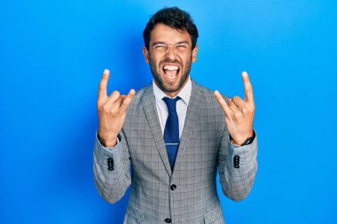 Sakallı, takım elbiseli, kravatlı, çılgın bir ifadeyle bağıran yakışıklı adam elleri havada rock sembolü yapıyor. Müzik yıldızı. ağır kavram. 