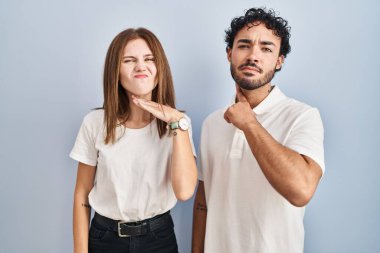 Young couple wearing casual clothes standing together cutting throat with hand as knife, threaten aggression with furious violence 