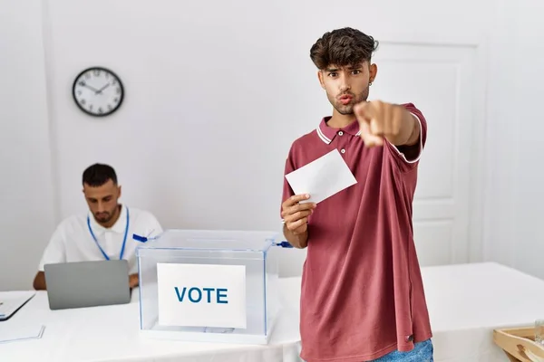 投票的年轻人把信封放进投票箱 用手指指向摄像机和你 自信地摆出一副严肃的样子 — 图库照片