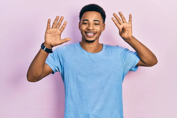 自信を持って幸せな笑顔ながら 若いアフリカ系アメリカ人の男は カジュアルな青のTシャツを着て指の数9で示すと指摘 — ストック写真