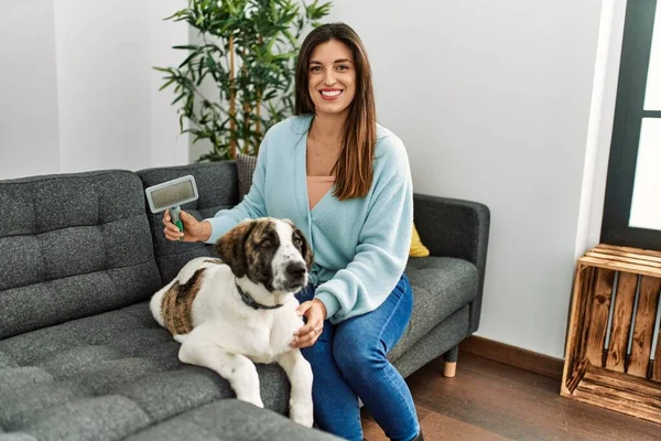 Young woman smiling confident using pet hair remover brush at home