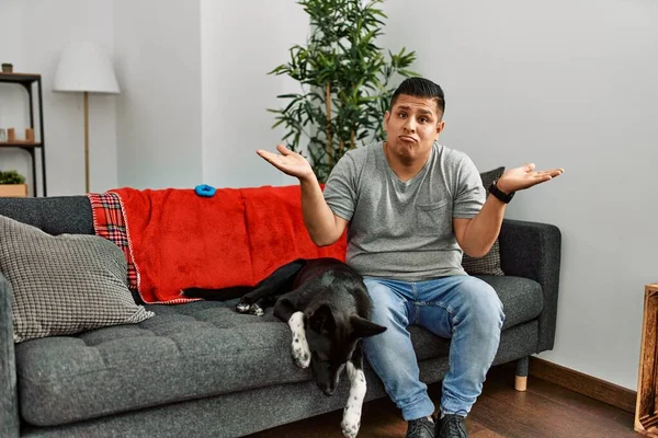 Jovem Latino Homem Cão Sentado Sofá Casa Sem Noção Confuso — Fotografia de Stock