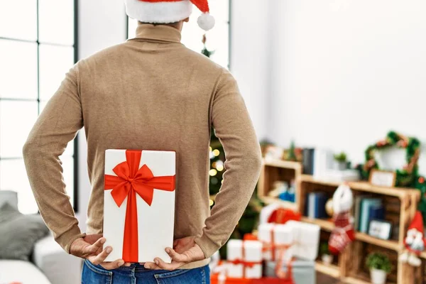 Young Hispanic Man Holding Christmas Gift His Back Home — Stockfoto