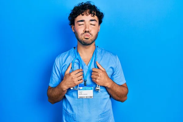 Young Hispanic Man Wearing Blue Male Nurse Uniform Puffing Cheeks — Zdjęcie stockowe