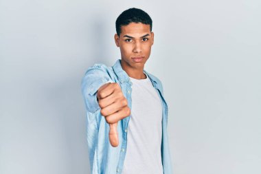 Young african american guy wearing casual clothes looking unhappy and angry showing rejection and negative with thumbs down gesture. bad expression. 