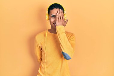 Genç Afrikalı Amerikalı adam müzik dinliyor. Kulaklıkla bir gözünü kapatıyor. Yüzünde kendine güvenen bir gülümseme ve şaşırtıcı bir duygu var.. 