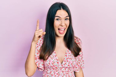 Yazlık elbise giyen genç esmer kadın başarılı bir fikri işaret ediyor. Heyecanlı ve mutlu. Bir numara.. 