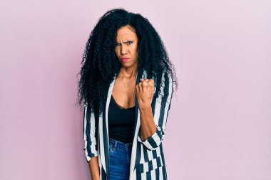 Orta yaşlı Afro-Amerikalı kadın, günlük kıyafetler giyiyor kızgın ve kızgın yumruk kaldırıyor öfkeyle bağırırken sinirli ve öfkeli. öfke ve agresif konsept. 