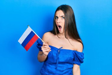 Genç esmer ergen elinde Rusya bayrağı tutarken ağzı açık kalmış, korkmuş ve hayrete düşmüştü. 