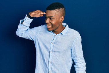 Genç, Afro-Amerikan bir adam günlük giysiler giyiyor çok mutlu ve gülümsüyor başlarını kaldırıp uzaklara bakıyor. arama kavramı. 