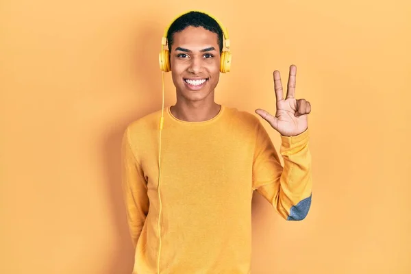 Joven Afroamericano Chico Escuchando Música Usando Auriculares Mostrando Apuntando Hacia —  Fotos de Stock