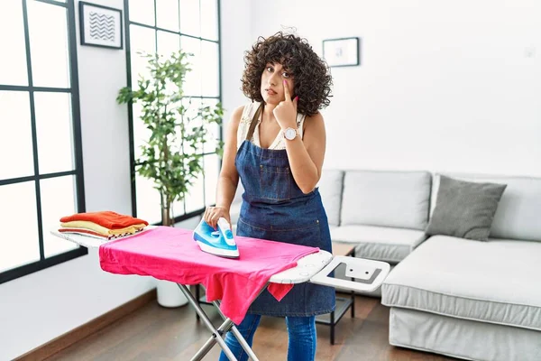 Ortadoğulu genç bir kadın evde kıyafetlerini ütülüyor. Gözünü dikip jestini izliyor. Şüpheli bir ifade. 