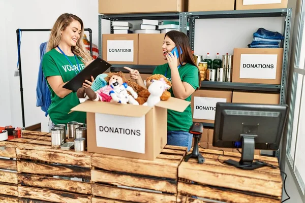 Yardım merkezinde çalışmaktan mutlu gülümseyen iki genç gönüllü kadın. Gülümseyen mutlu bir kız akıllı telefonda konuşuyor..