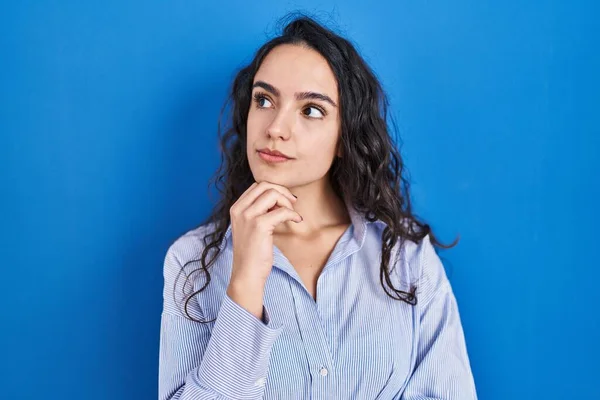 Young Brunette Woman Standing Blue Background Hand Chin Thinking Question — Zdjęcie stockowe