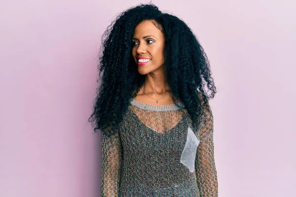 Orta yaşlı Afro-Amerikalı kadın günlük giysiler giyiyor, rahat profil pozu veriyor doğal bir yüzü ve kendine güvenen bir gülüşü var.. 