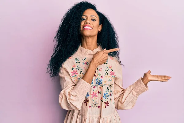 Orta yaşlı Afro-Amerikalı kadın gündelik giysiler giyip kameraya hayret ediyor ve gülümsüyor.. 