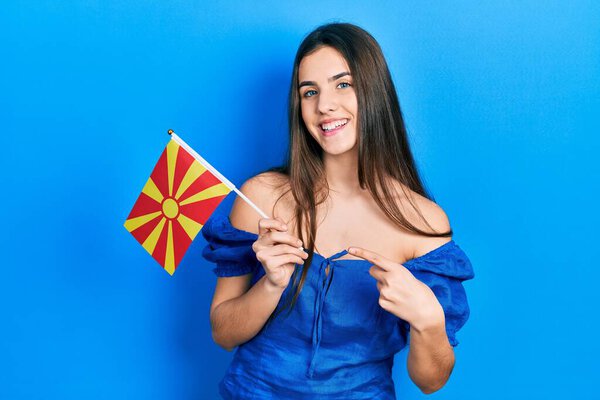 Молодая брюнетка-подросток с македонским флагом улыбается счастливо показывая рукой и пальцем 
