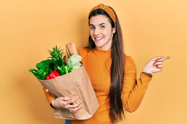 Joven Morena Adolescente Sosteniendo Bolsa Papel Con Comestibles Pensando Concentrado —  Fotos de Stock