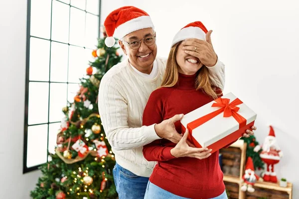 Casal Hispânico Meia Idade Sorrindo Feliz Abraçando Segurando Presente Natal — Fotografia de Stock