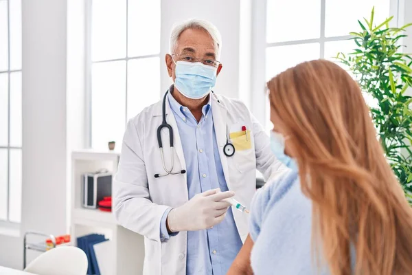 Lekarz Średnim Wieku Noszący Maskę Medyczną Szczepiący Pacjenta Klinice — Zdjęcie stockowe