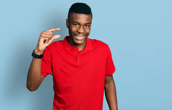 年轻的非洲裔美国人穿着休闲的红色T恤 微笑着 自信地摆姿势 手拿着小尺寸的标志 手拿着手指 手拿着相机 计量概念 — 图库照片