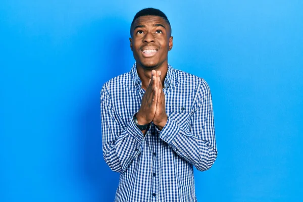年轻的非洲裔美国男子身穿休闲装 双手牵着手乞讨和祈祷 脸上带着希望的表情 非常情绪化和忧虑 — 图库照片