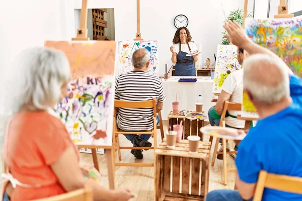 Bir grup orta yaşlı öğrenci resim stüdyosunda resim dersi alıyor..