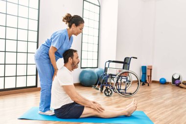 Orta yaşlı erkek ve kadın fizik tedavi kliniğinde rehabilitasyon seanslarına konsantre oluyorlar.