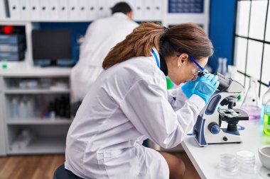 Laboratuvarda mikroskop kullanan orta yaşlı erkek ve kadın bilim adamları