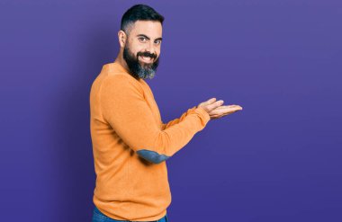 Kış süveteri giyen İspanyol sakallı adam avuçlarını açıp fotokopi alanını gösteriyor, gülümseyerek mutlu bir gülümseme sergiliyor. 