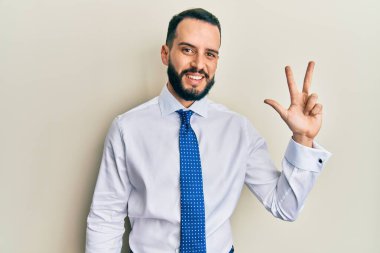 Sakallı, iş kravatlı, üç numaralı parmaklarıyla kendini beğenmiş ve mutlu gülümseyen genç adam.. 