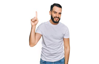 Gündelik beyaz tişört giyen sakallı genç adam başarılı bir fikri işaret ediyor. Heyecanlı ve mutlu. Bir numara.. 