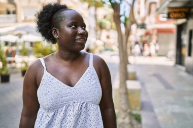 Genç Afrikalı Amerikalı kadın gülümseyerek şehirde mutlu mesut duruyor..