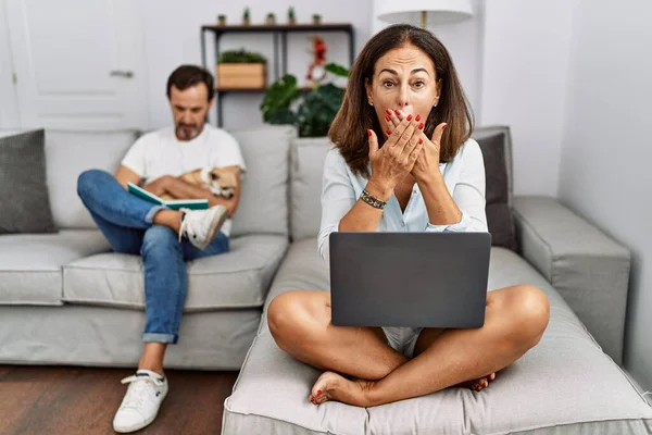 Hispanic Middle Age Couple Home Woman Using Laptop Shocked Covering — Stockfoto