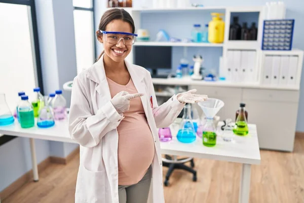 Молодая Беременная Женщина Работающая Лаборатории Удивлялась Улыбалась Камеру Показывая Рукой — стоковое фото