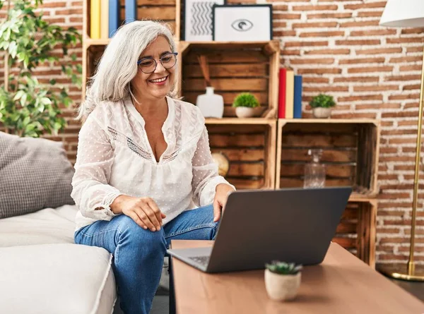 Orta yaşlı bir kadın evdeki koltukta oturmuş video görüşmesi yapıyor.